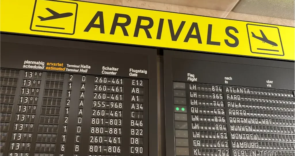 Arrivals banner at airport showing flights numbers and countries